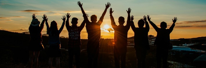 silhouette of people at sunset with their hands in the air